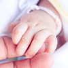 Adult's hand holding a newborn baby's hand