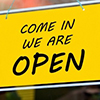 come in we are open sign hanging on a window door outside a restaurant, store, office or other