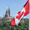 Canadian flag waving with Parliament Buildings hill and Library in the background