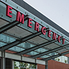 View of ER sign outside hospital - ambulance in background