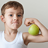 boy with green apples showing biceps 