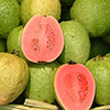 Basket of guavas with four halves showing red flesh