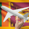 person holding model of plane in front of Sri Lanka flag
