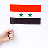 Symbol of the national day of Syria concept with flag in hand on white background top view