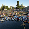 hundreds of spectators in seats, boats, rafts, kayaks, canoes at an outdoor concert on the water in 