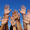 Volunteer written in cloudy text  over blue sky background. hands raised in air below words