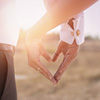 groom and bride forming heart shape from hands