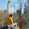Young woman looking at skyscrapers while sitting on a rock 