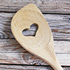 Wooden spoon on wood planks - heart shape curved in middle of spoon